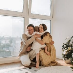 A joyful family hugging tightly near a window, radiating warmth and togetherness.